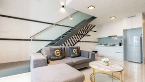 A modern living room with a sofa, a coffee table, and a staircase. - Guestonic EkoCheras Cozy Studio (Kuala Lumpur)