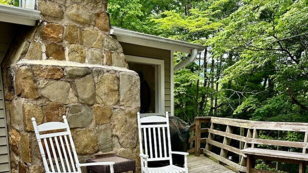 An outdoor patio with stone walls, wicker furniture, and a wooden deck.