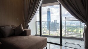 A modern living room with a large window, a sofa, and a view of a cityscape. - Guestonic Continew Comfy Home (Kuala Lumpur)