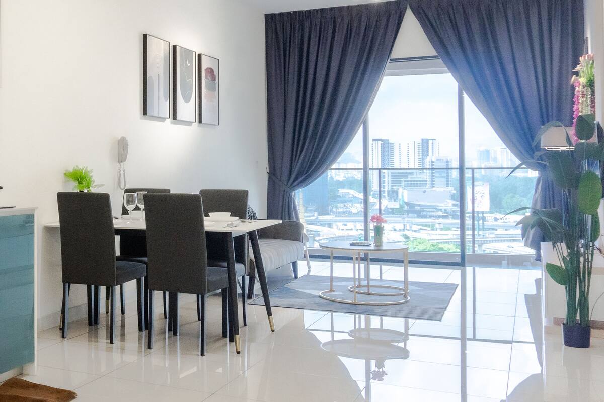 Ein stilvoller Essbereich mit Tisch, Stühlen und Blick auf die Stadt durch große Fenster.