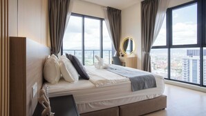 A modern hotel room with a large bed, a bedside table with a mirror, and a view of the cityscape through large windows. - Guestonic Continew Comfy Home (Kuala Lumpur)