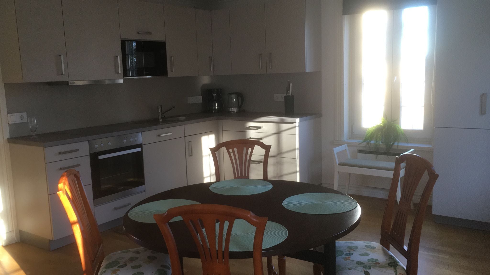 Una cocina moderna con comedor, que incluye horno empotrado, microondas y una mesa de comedor con sillas.