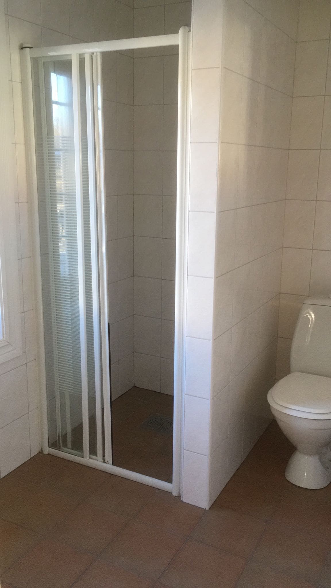 Une salle de bain avec une douche à parois de verre, des toilettes et des murs carrelés.