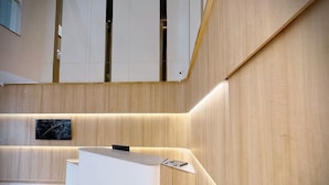 A modern reception desk with a minimalist design, wooden paneling on the walls, and a marble accent piece. - ASAR by Orion Hotels (New Delhi)