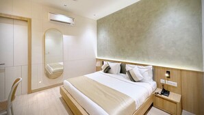 A modern hotel room with a large bed, a bedside table with a phone, a mirror, and a ceiling fan. - ASAR by Orion Hotels (New Delhi)