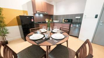 Uma cozinha moderna com uma mesa de jantar para quatro pessoas, equipada com frigorífico, micro-ondas e máquina de lavar loiça.