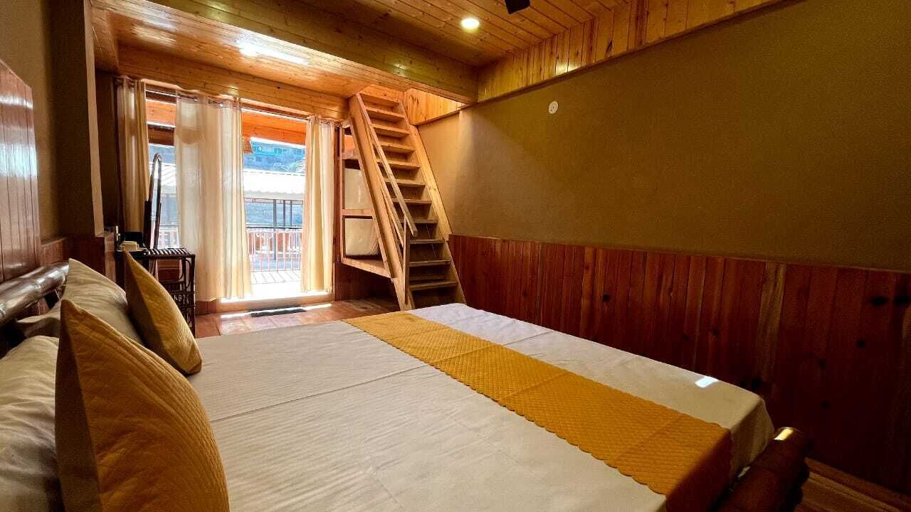 A bedroom with a bed, wooden walls, a staircase, and a balcony.