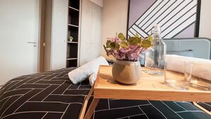 A neatly arranged bedroom with a bed, a bedside table with a vase of flowers, a glass of water, and a towel. - Guestonic Millerz Luxury Home (Kuala Lumpur)
