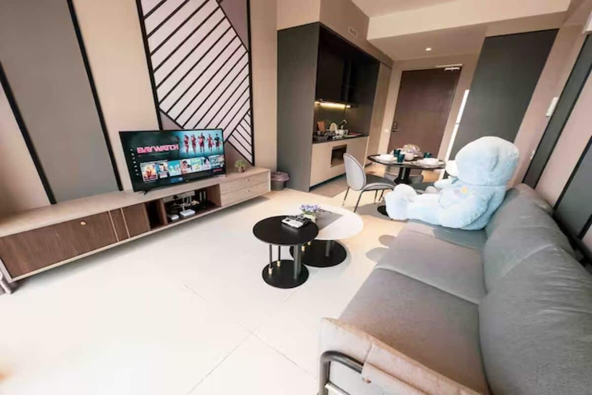 Una sala de estar moderna con un televisor de pantalla plana, un sofá, una mesa de centro y una pequeña zona de comedor.