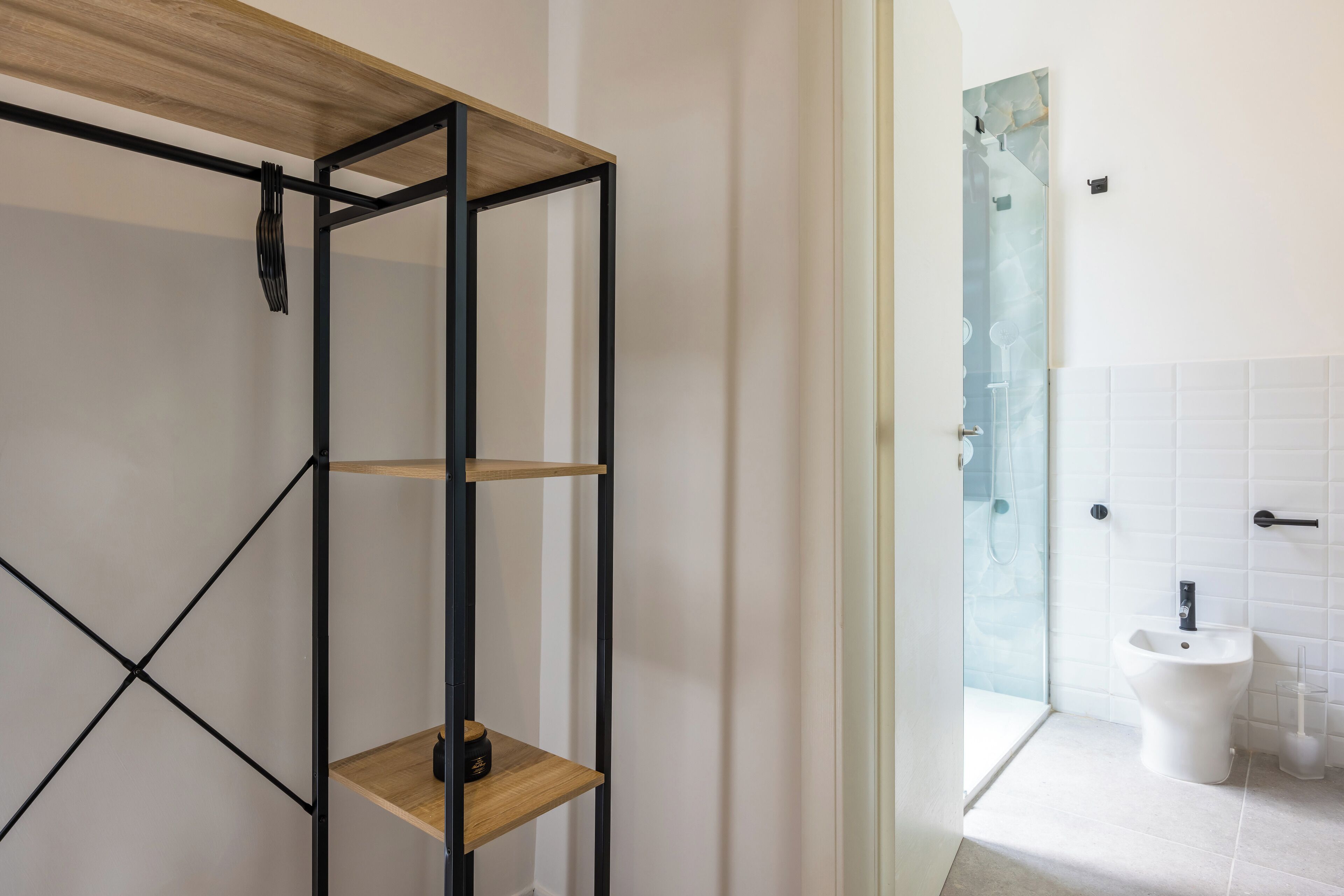 A bathroom with a white tiled wall, a white sink, and a glass shower enclosure.