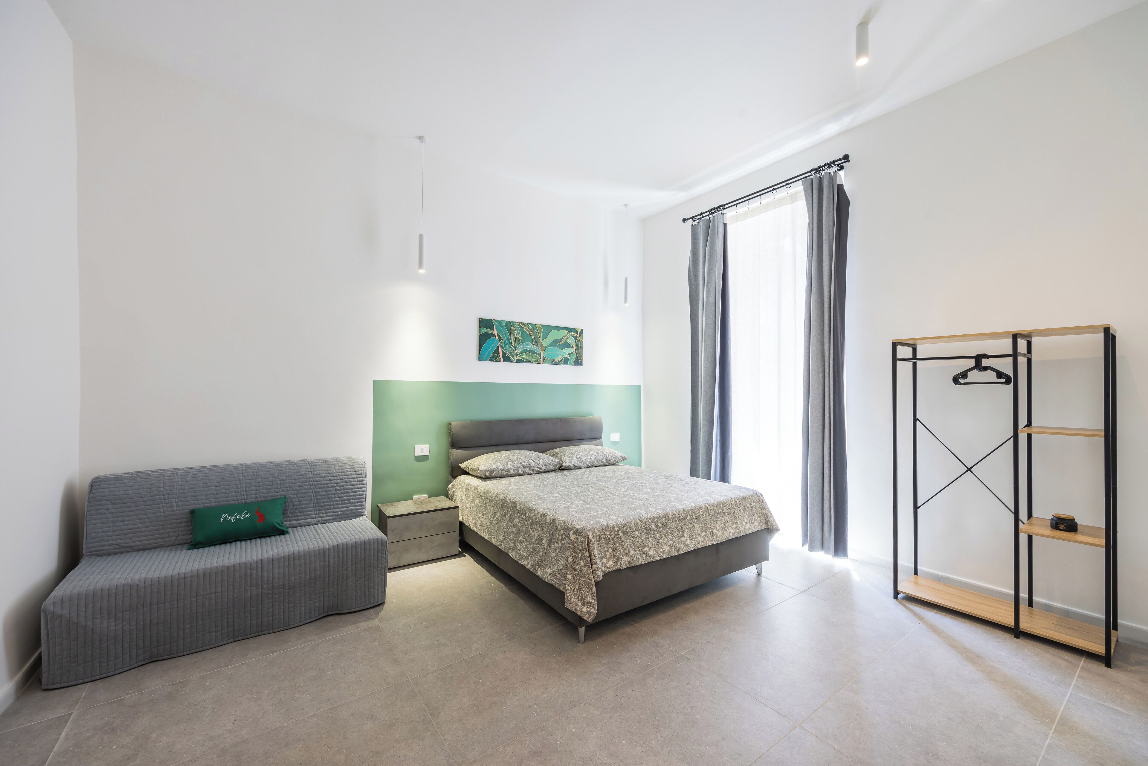 Un dormitorio moderno con una cama, un sofá, un armario y una pared verde.