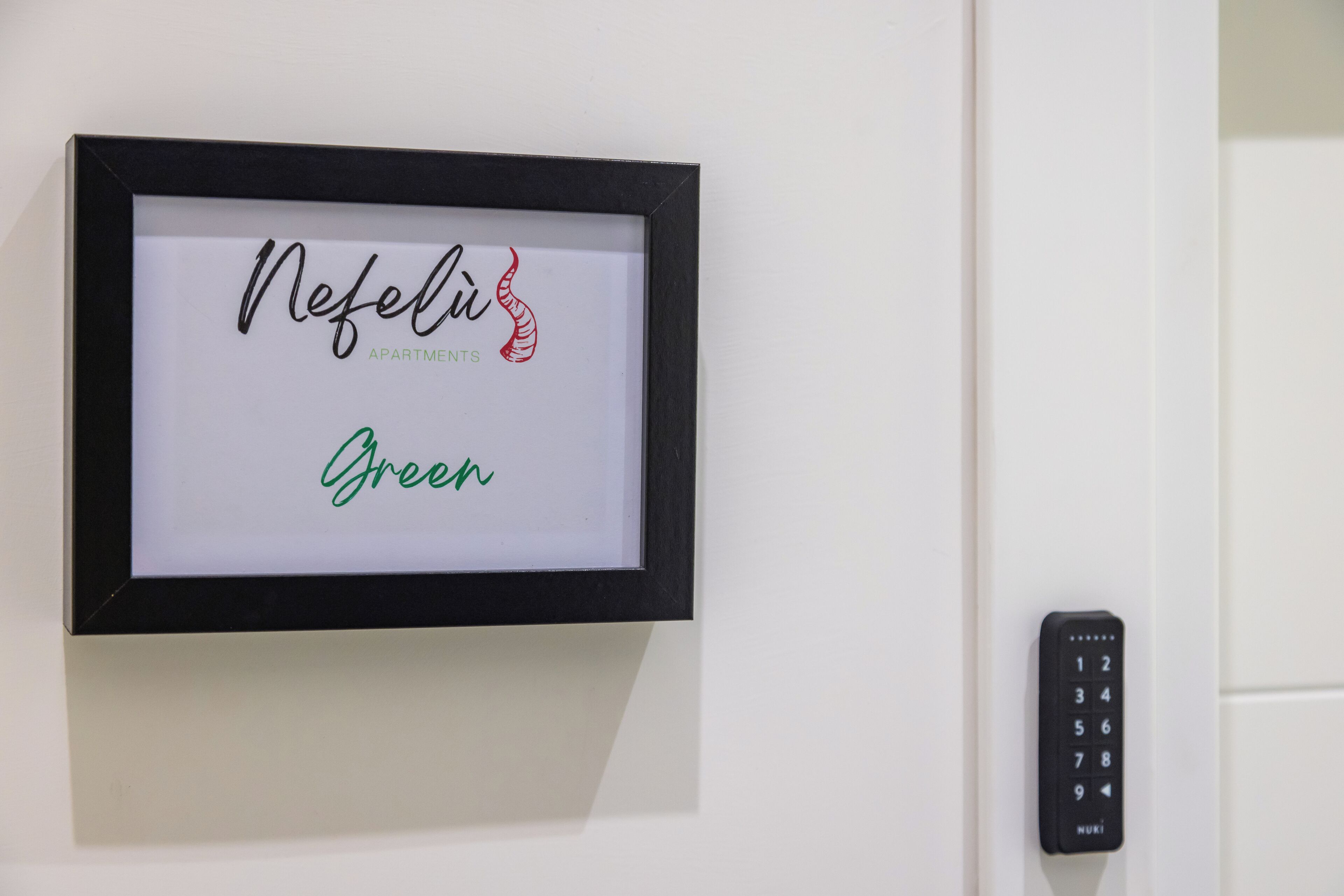 A framed sign with the name "Nefeli Apartment" and the word "Green" in cursive.
