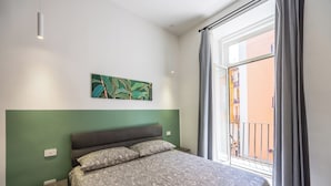 A bedroom with a bed, a green wall, a window with curtains, and a painting. - Nefelu apartments (Naples)