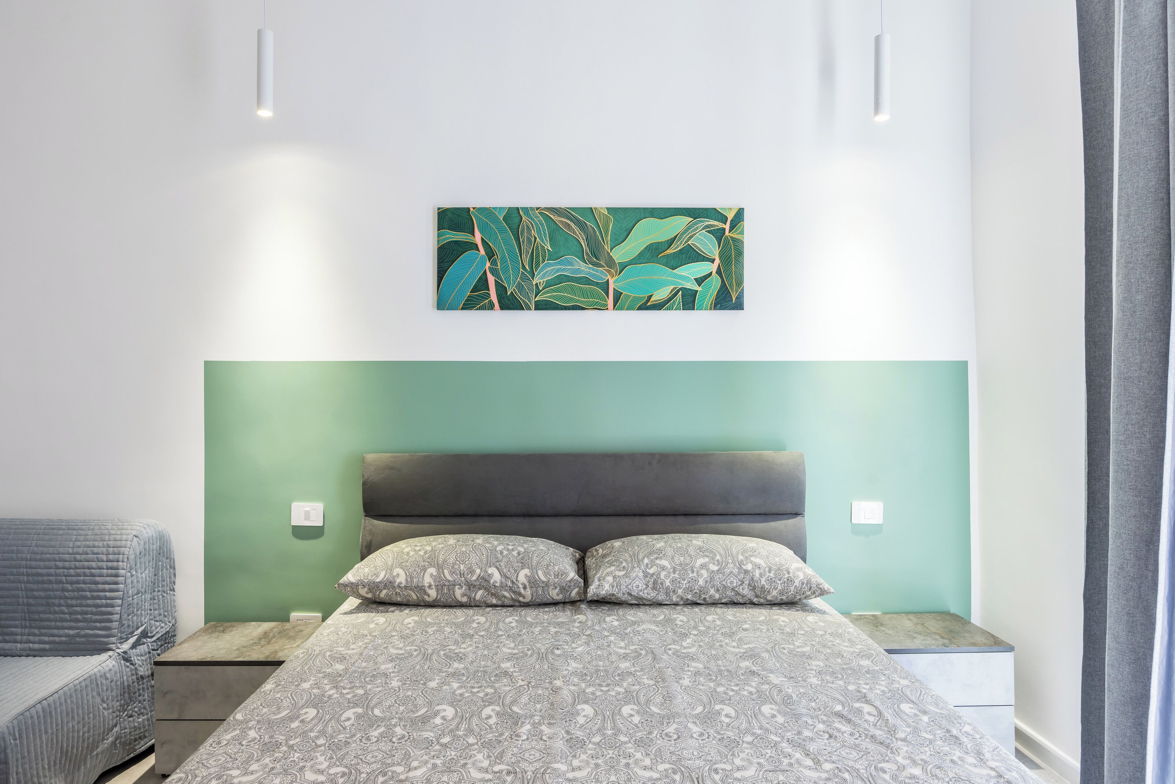 Une chambre à coucher comprenant un lit, des tables de chevet, une table de nuit et une œuvre d’art accrochée au mur.