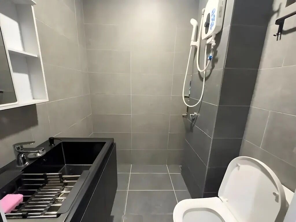 A modern bathroom with a shower, toilet, and a built-in sink with a soap dish.