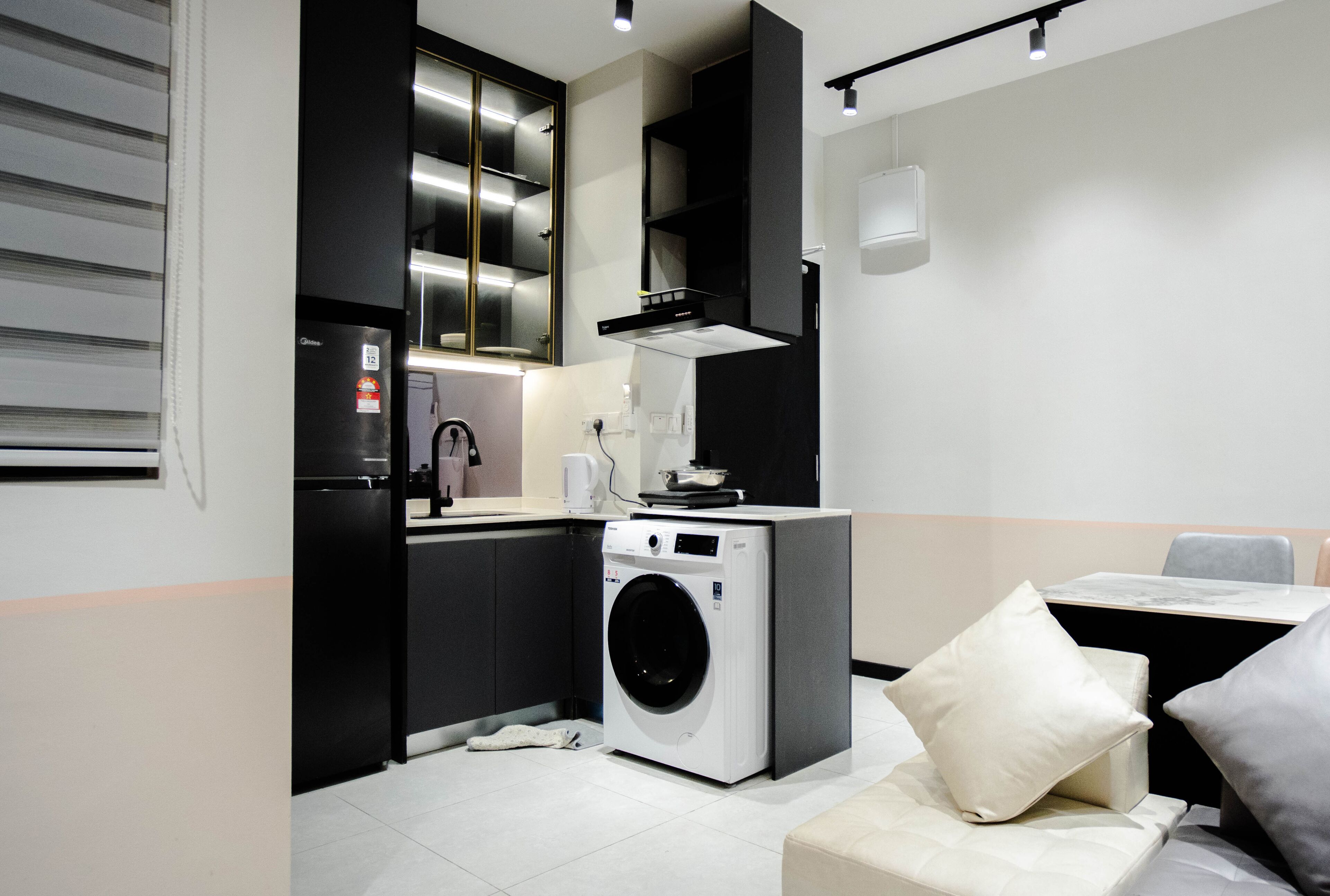 A compact kitchen with a built-in washer and dryer, a small dining area with a table and chairs, and a modern design with black and white color scheme.