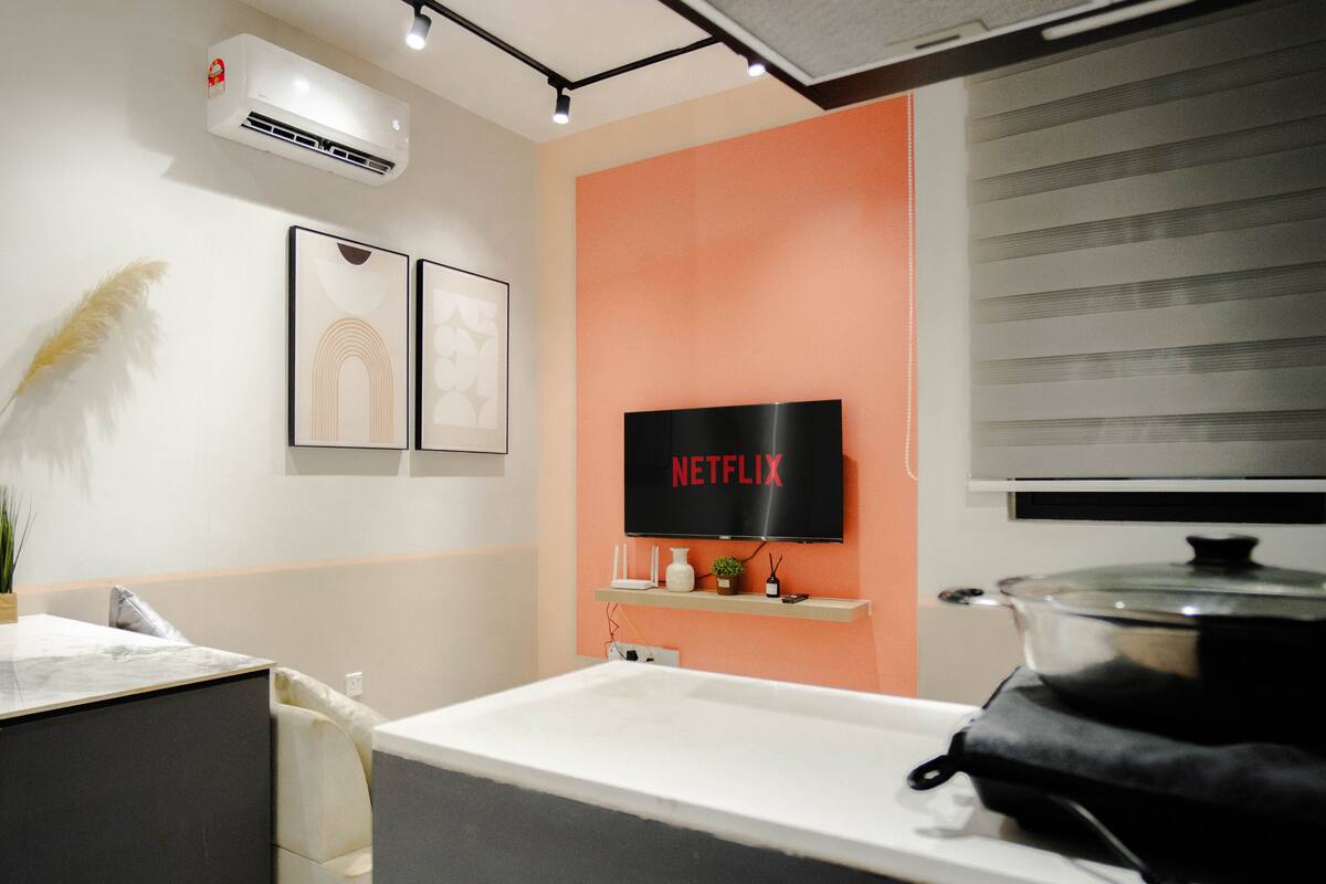 A modern kitchen with a large stove, a sink, and a wall-mounted television displaying the Netflix logo.