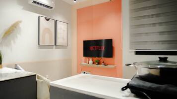 A modern kitchen with a large stove, a sink, and a wall-mounted television displaying the Netflix logo.