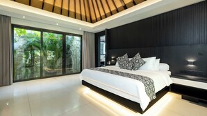 A modern bedroom with a large bed, a dark headboard, and a view of greenery through large windows. - Villa Kubu Dewi Sri by Villa Finder (Canggu)