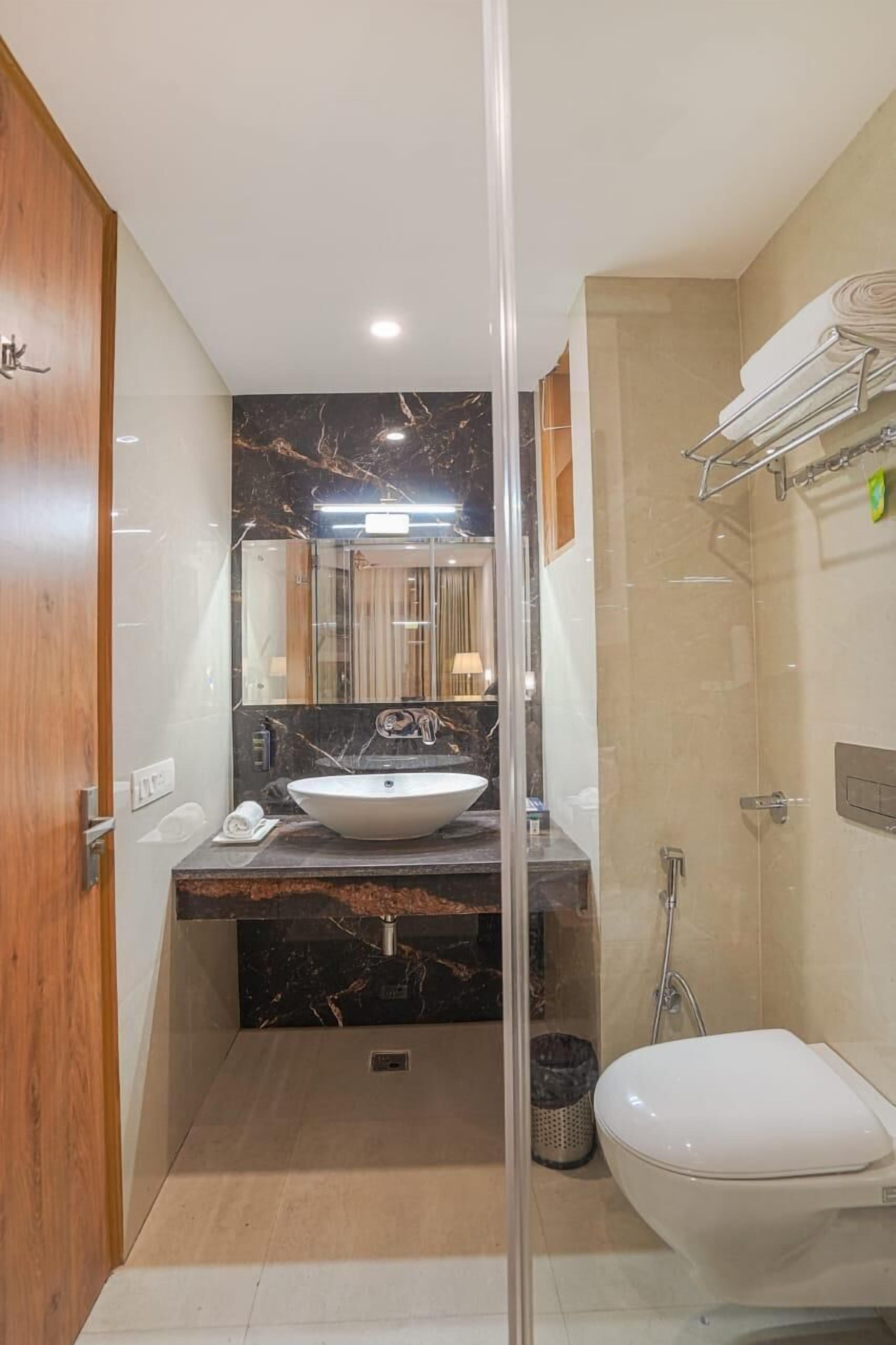 Ein modernes Badezimmer mit Marmorwaschbecken, einer Duschkabine aus Glas und einer Toilette.