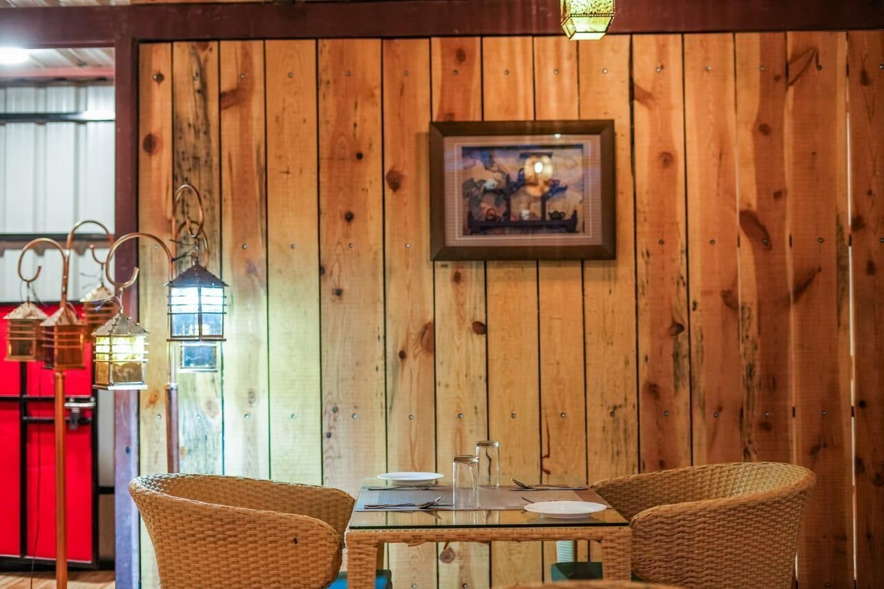 Pareti rivestite in legno con un quadro incorniciato, sedie in vimini e un tavolo apparecchiato per la cena.
