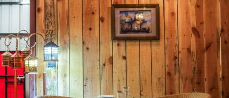 Pareti rivestite in legno con un quadro incorniciato, sedie in vimini e un tavolo apparecchiato per la cena.