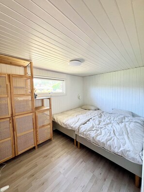 A bedroom with a bunk bed, a wooden wardrobe, and a window. - Charming summer house on a secluded plot (Glesborg)