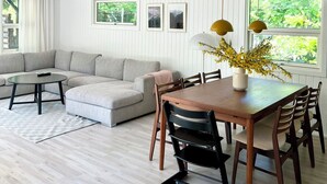 A modern living room with a sectional sofa, a wooden dining table with chairs, and a ceiling with horizontal lines.