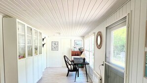 A corridor with wooden paneling, a dining area with a table and chairs, and a plant.