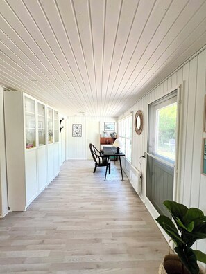 A corridor with wooden paneling, a dining area with a table and chairs, and a plant. - Charming summer house on a secluded plot (Glesborg)