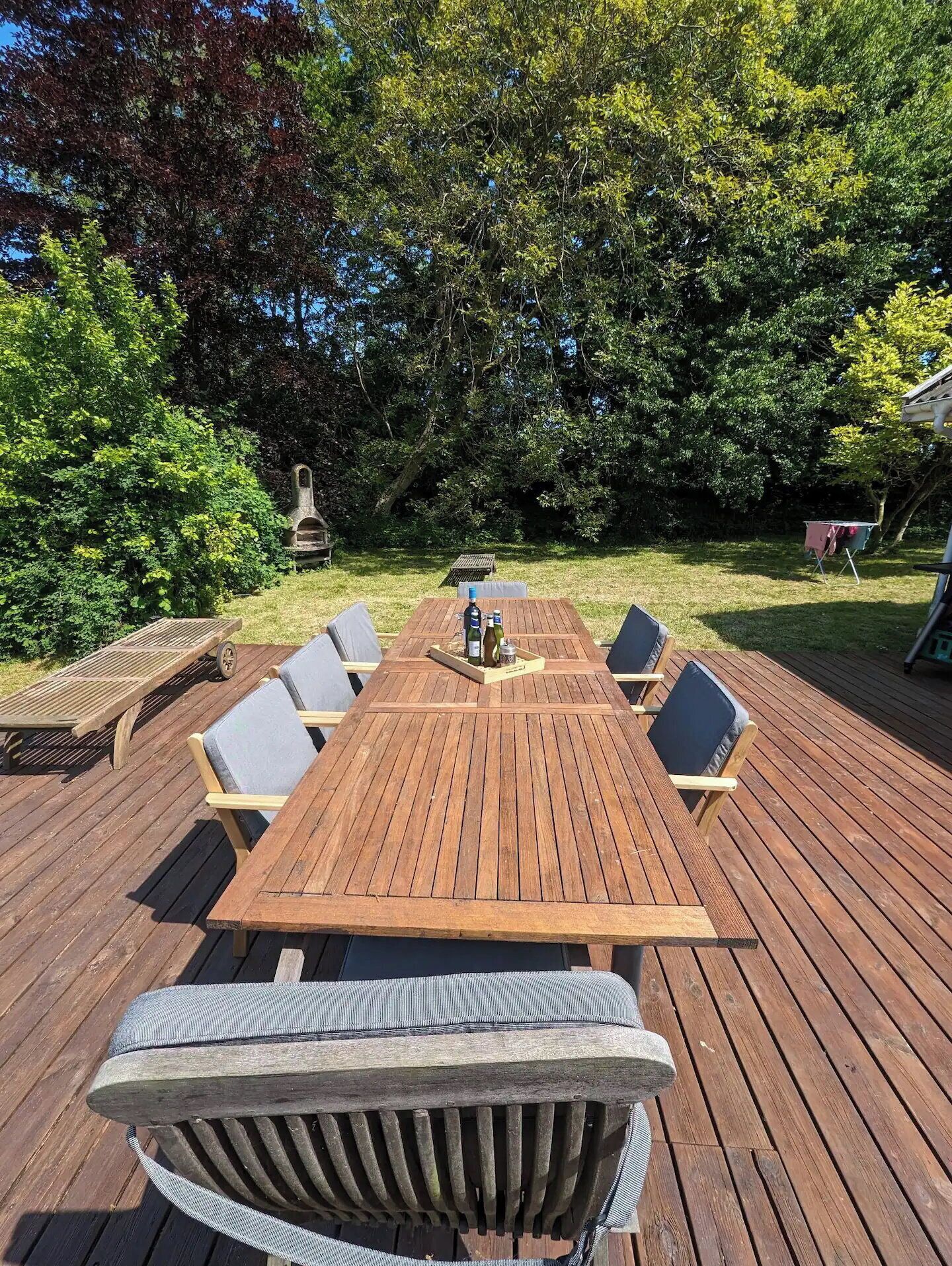 Una terraza de madera con una mesa y sillas, rodeada de árboles.