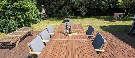 Una terraza de madera con una mesa y sillas, rodeada de árboles.