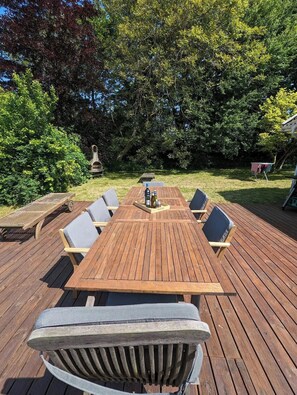 Eine Holzterrasse mit Tisch und Stühlen, umgeben von Bäumen.
