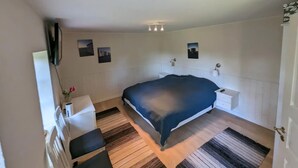 A bedroom with a bed, bedside tables, a dresser, a mirror, and wall-mounted artwork. - Cozy country estate in Vesterborg. (Vesterborg)