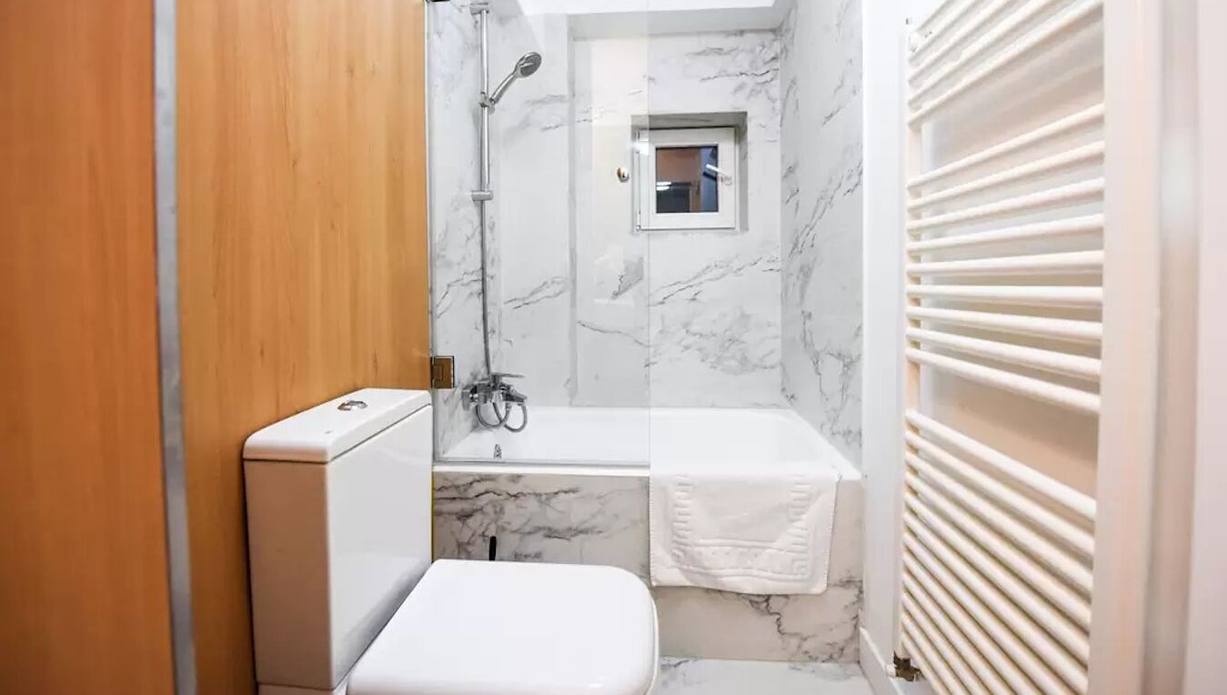 Un baño pequeño con inodoro, ducha y un ventanal.