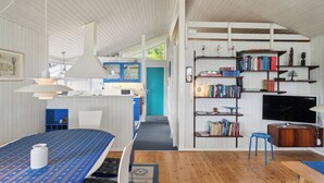 Un soggiorno moderno con un divano, un tavolino, una libreria, una TV e un'area pranzo con tavolo e sedie.
