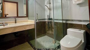 Un baño moderno con ducha envuelta en vidrio, inodoro blanco y tocador con espejo.