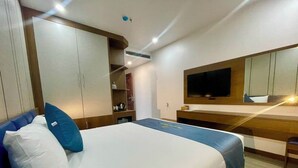 Habitación de hotel con cama, escritorio, televisión y armario.