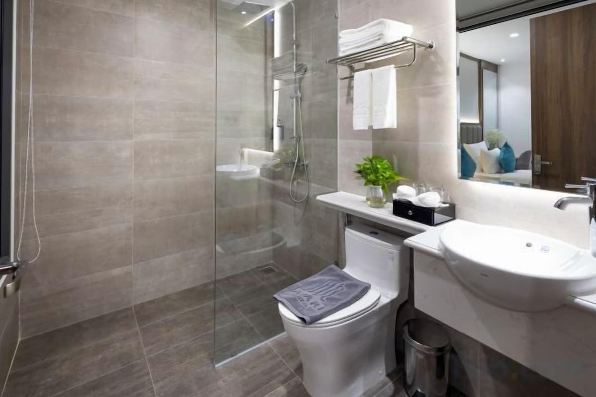 A modern bathroom with a glass shower enclosure, a toilet, a sink, and a mirror.