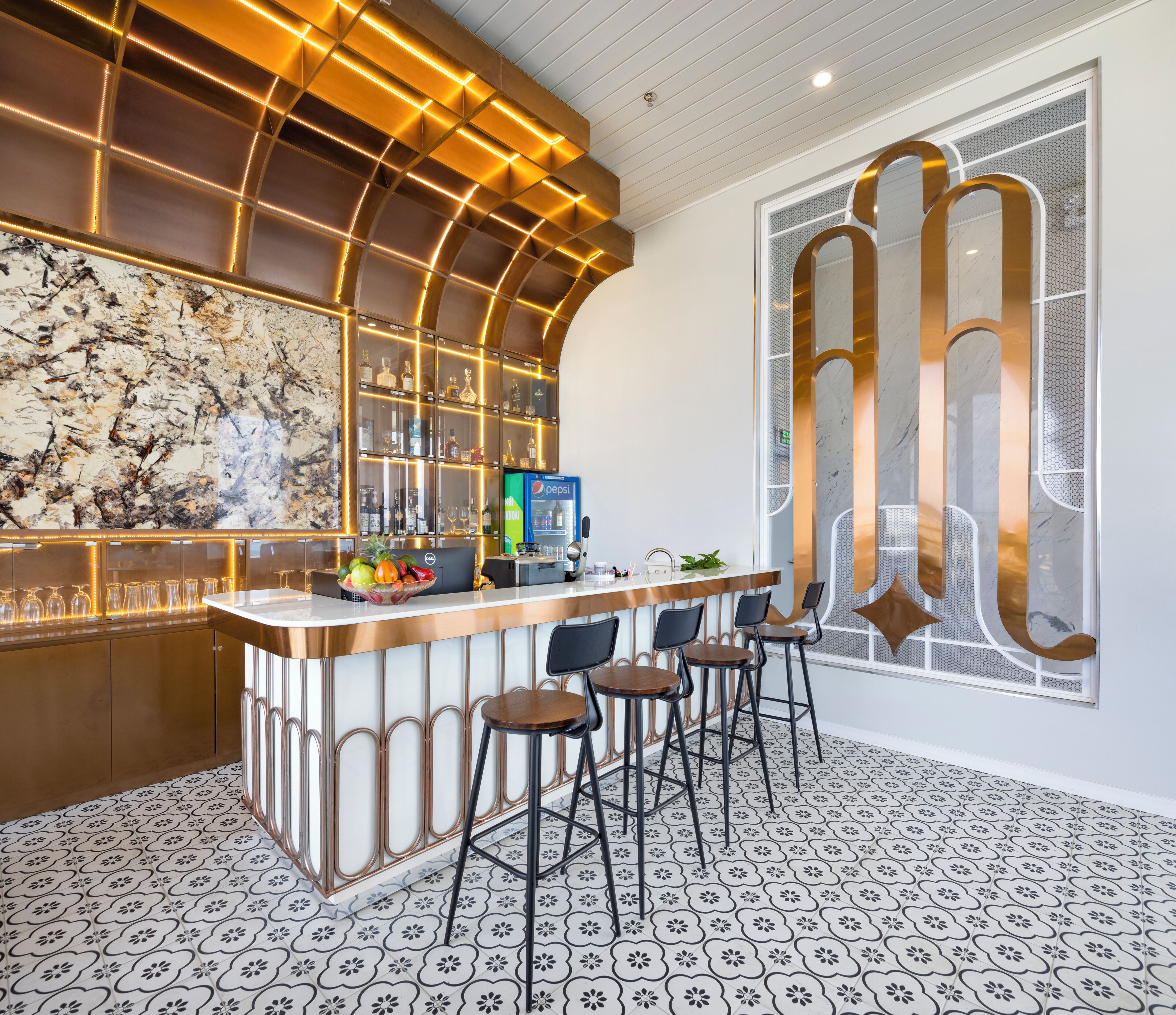 Un espace bar avec un mur en marbre, un réfrigérateur à boissons et un sol à motifs.