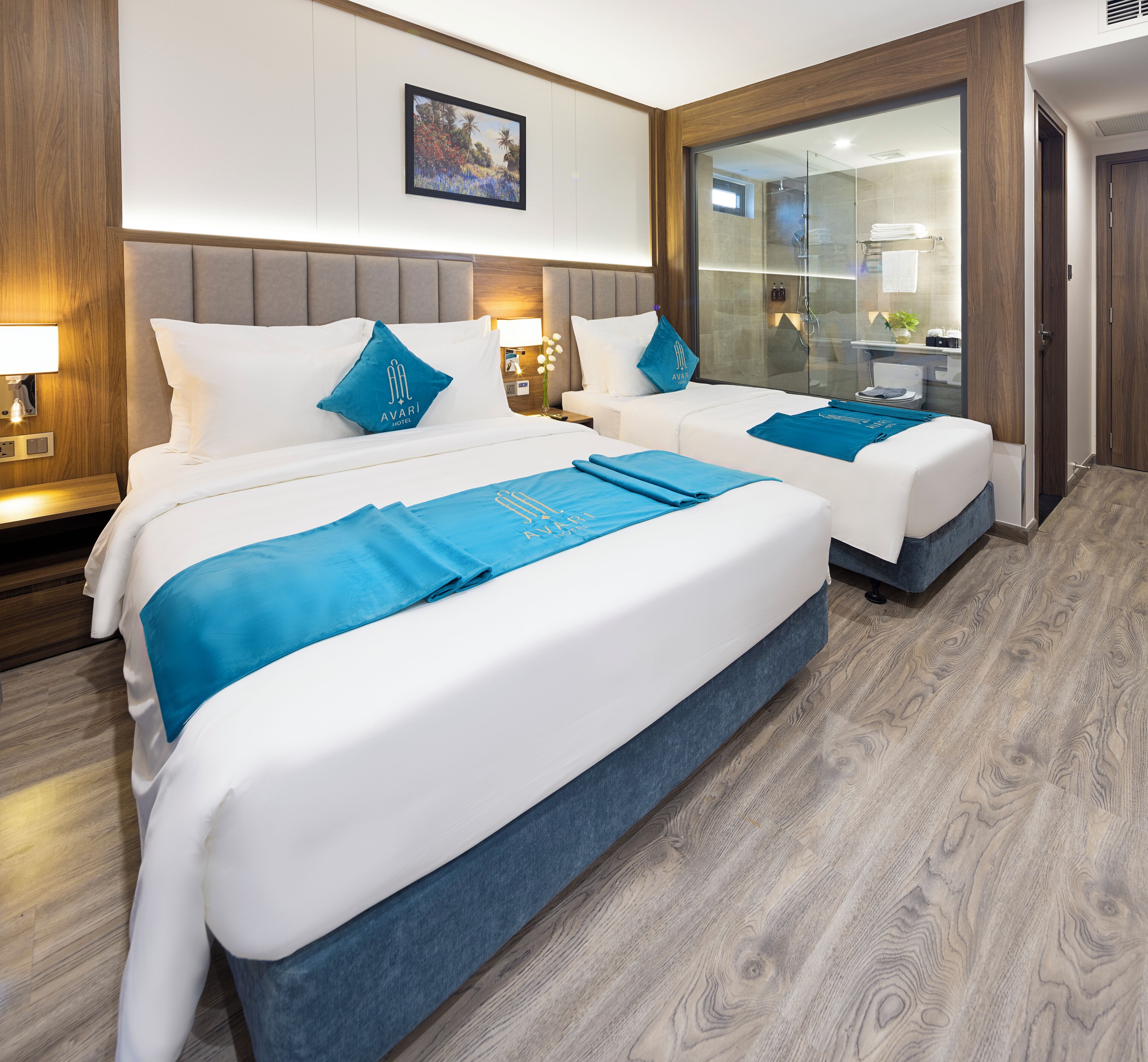 A hotel room with two beds, a large mirror, a shower area, and a wooden floor.