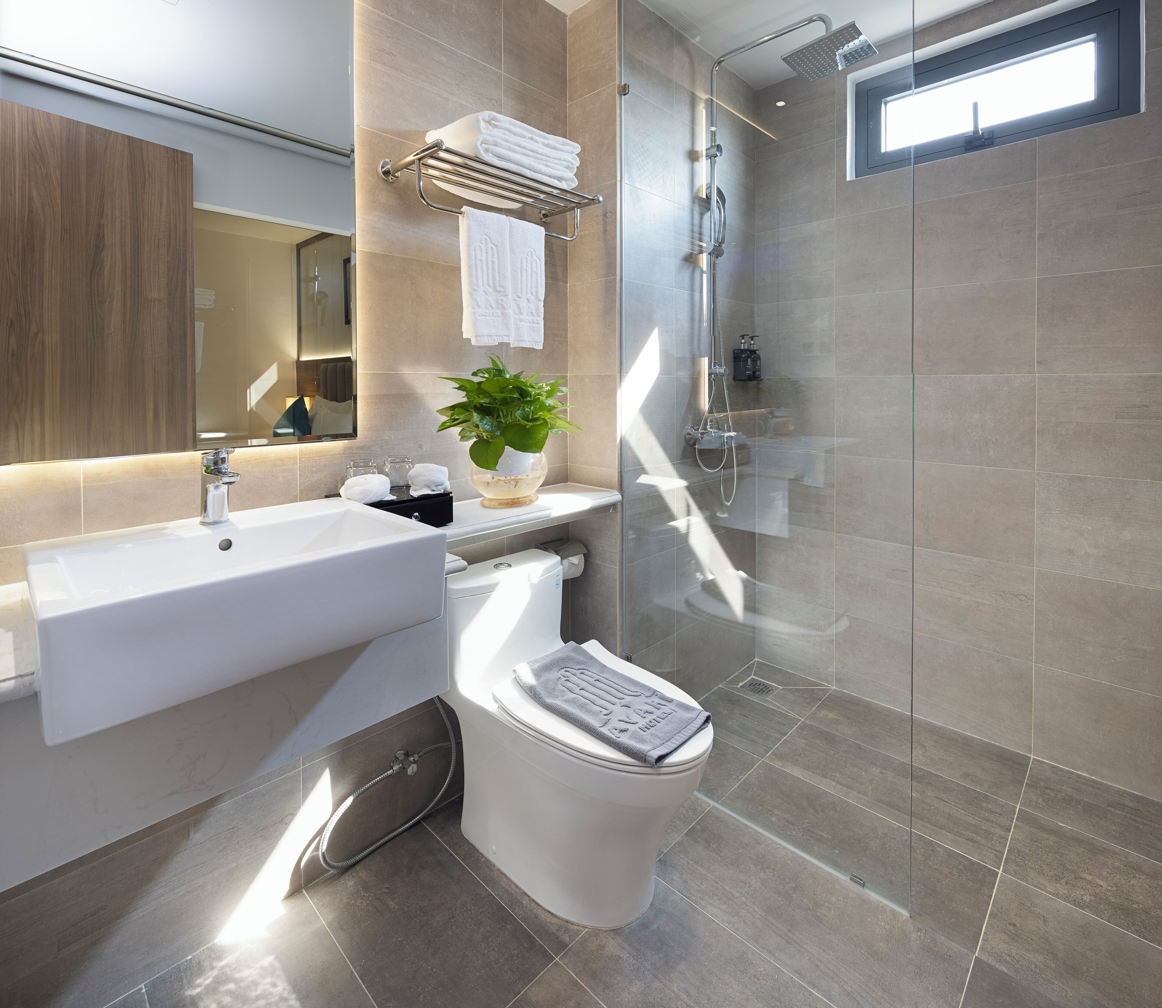 A modern bathroom with a glass-enclosed shower, a white sink, and a toilet.