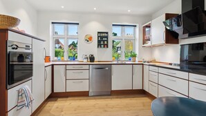 A modern kitchen with white cabinets, a stainless steel dishwasher, and a large window.