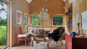 A wooden-paneled room with a dining table, chairs, a chandelier, and a dresser. - Unique private idyll (Vesterborg)