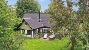 A house with a sloped roof, a chimney, and a small garden with a chair and table. - Unique private idyll (Vesterborg)