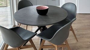 Una cocina moderna con comedor, una mesa redonda con un bol y sillas grises.