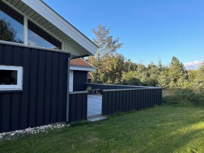 Moderni talo, jossa on tumma julkisivu, selkeästi näkyvä ikkuna ja patioalue.