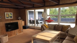 A living room with a sofa, a coffee table, a TV, and a large window.