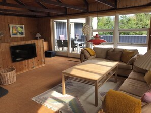 A living room with a sofa, a coffee table, a TV, and a large window.
