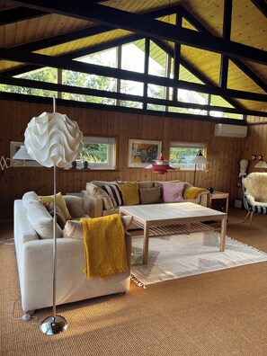 A cozy living room with a wooden ceiling, a sofa, a coffee table, and a hanging light fixture.